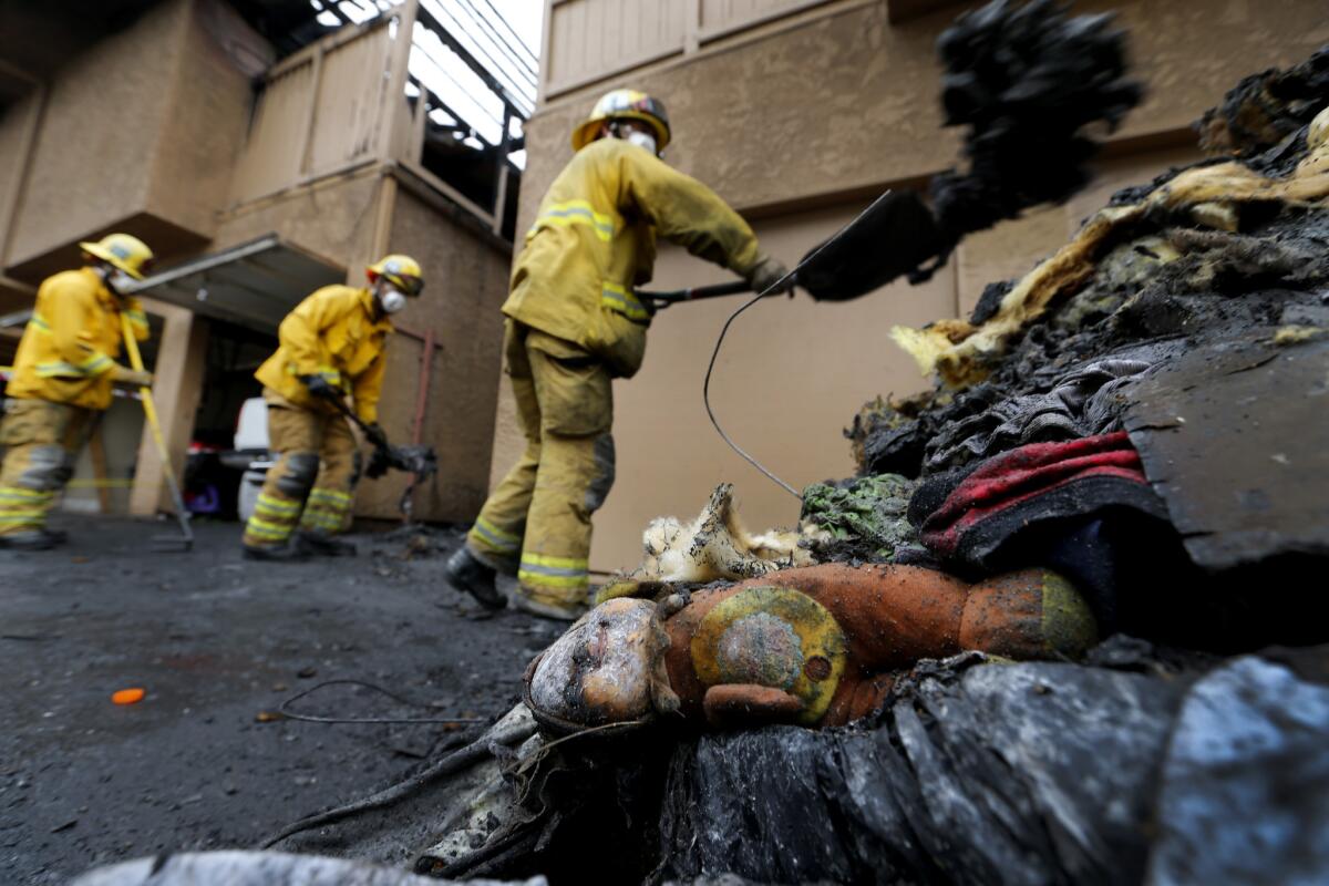 A child's doll lies discarded as Orange County Fire Authority firefighters clean up after a condo fire in San Juan Capistrano on Tuesday.