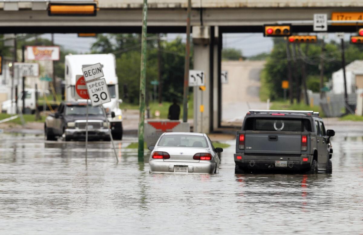 A motorist stops to help another driver stranded in high water in Dallas on Saturday. With more rain expected, the National Weather Service has issued a flood watch for portions of Texas.