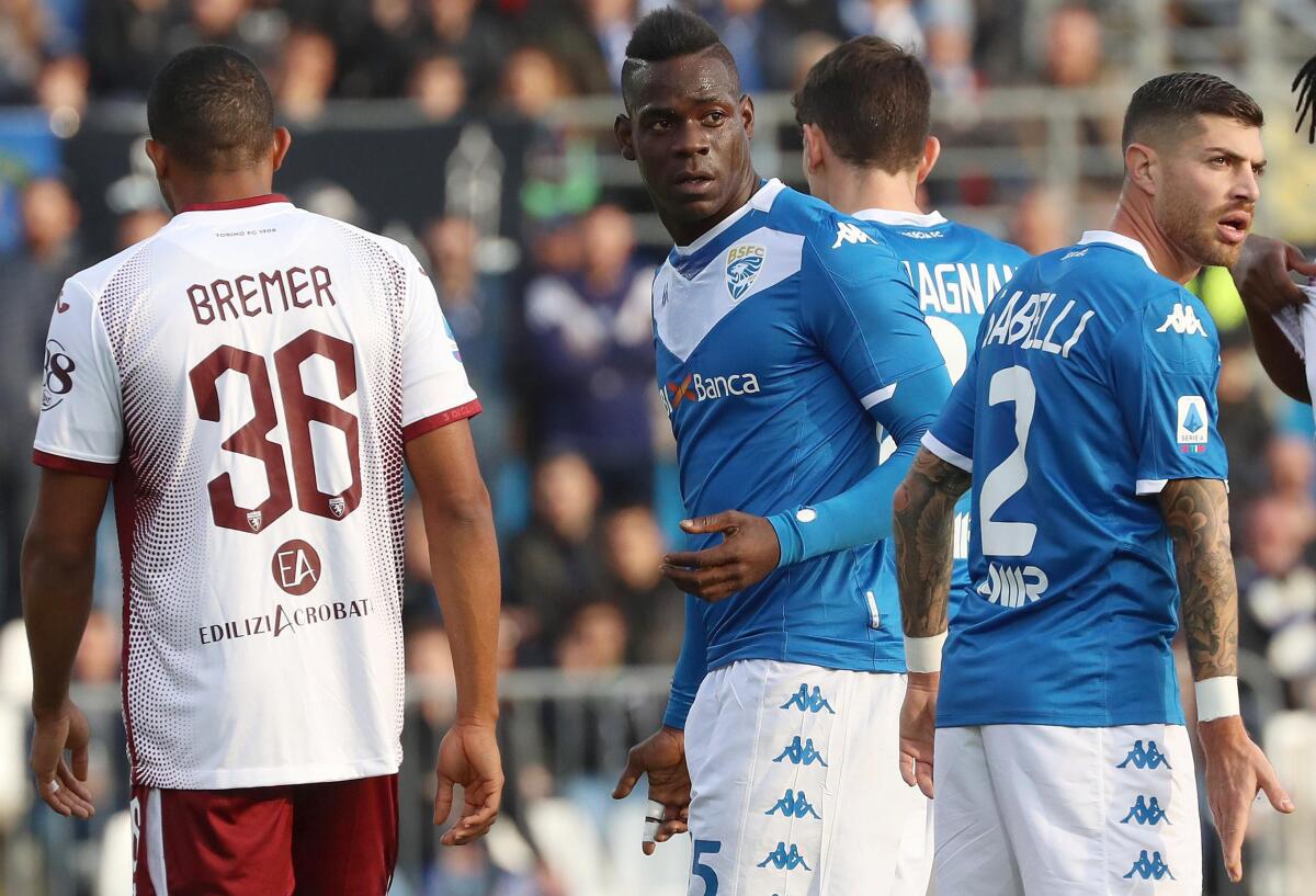 FILE - In this Saturday, Nov. 9, 2019 filer, Brescia's Mario Balotelli, center, walks on the pitch during the Serie A soccer match between Brescia and Torino at the Mario Rigamonti Stadium in Brescia, Italy. Three leaders of the extreme-right Forza Nuova political party have been stopped by police for putting up a racist banner aimed at Brescia striker Mario Balotelli. The banner, which read Mario youre right, youre an African, was posted on a fence outside Juventus Allianz Stadium in Turin last month. The words Mario and African were written in red with the other words in black. The banner also featured a logo for the neo-fascist Forza Nuova party. (Filippo Venezia/ANSA via AP, File)