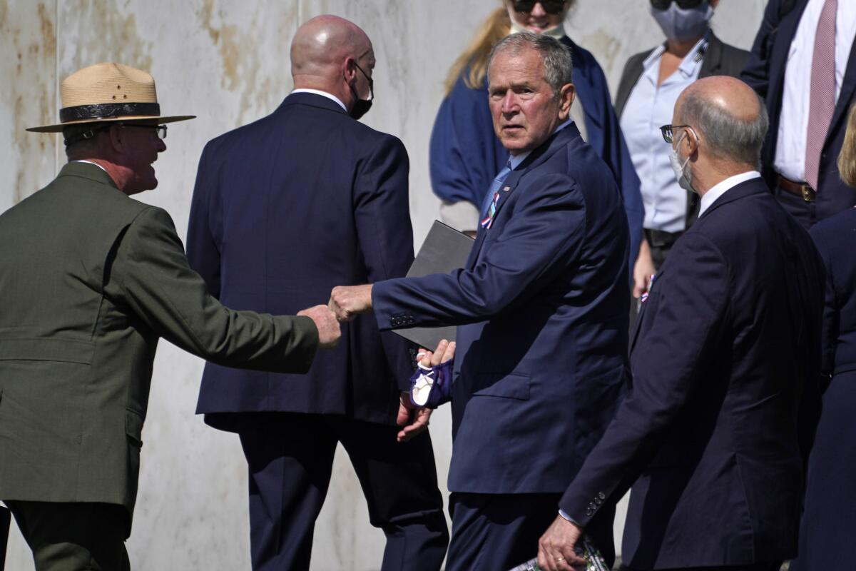 Former President George W. Bush, right center, bumps fists with Flight 93 National Memorial superintendent Stephen M. Clark, left, after participating in a Service of Remembrance at the Flight 93 National Memorial in Shanksville, Pa., Saturday, Sept. 11, 2021, as the nation marks the 20th anniversary of the Sept. 11, 2001 attacks. (AP Photo/Gene J. Puskar)