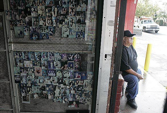 John Cabrera stands outside Cabrera's Market in Hawaiian Gardens, which has been part of the neighborhood since 1952, as generations of family photographs on the wall testify. Now Cabrera, the last of the family, is retiring and leasing the market to someone else.