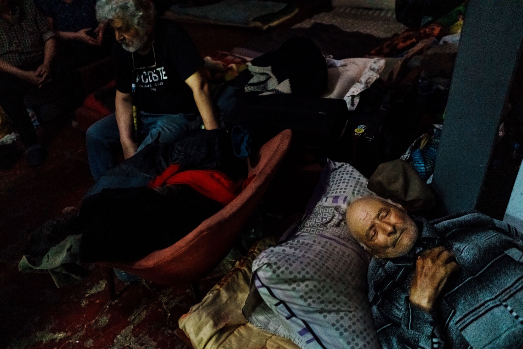 Several people sitting or lying down in a dark room 