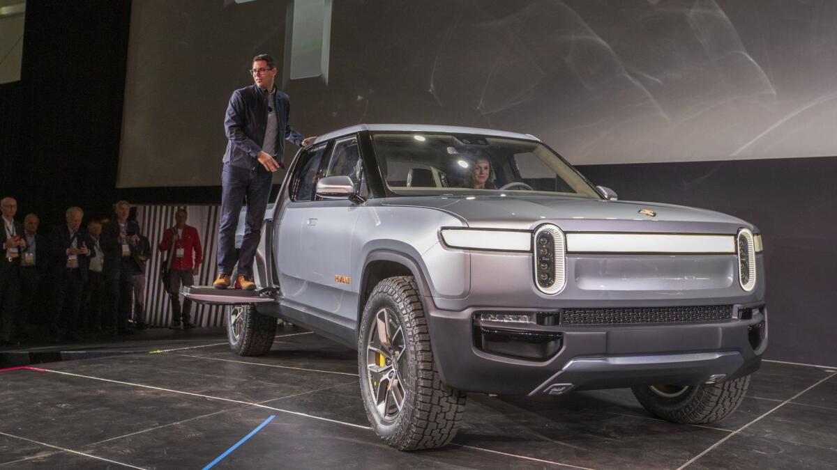 Rivian Chief Executive R.J. Scaringe perches on his company's R1T electric truck during the vehicle's debut at the Los Angeles Auto Show in November.
