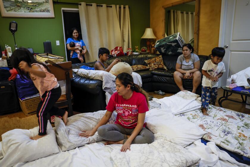 Kahului, Maui, Thursday, August 17, 2023 - Rochelle Valiente helps prepare her bed on the living room floor of the Relyn and Jowel Delfin. She and numerous other relatives displaced by the Lahaina fire, are living there until they find permanent housing. (Robert Gauthier/Los Angeles Times)