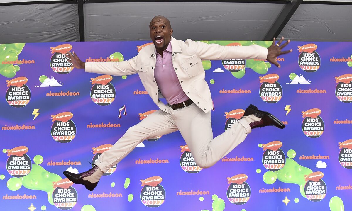 A man in a white suit leaps through the air as he arrives at an awards show.
