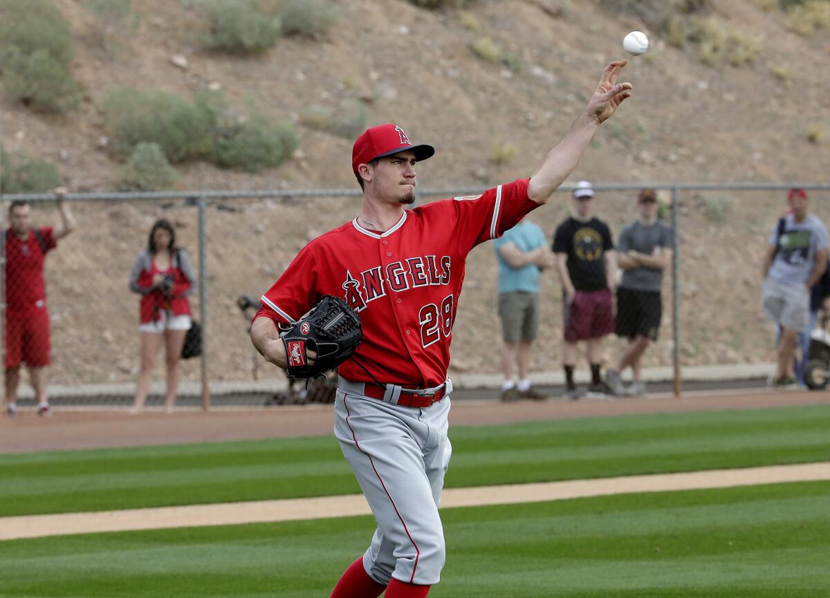 Angels starting pitcher Andrew Heaney throws to first as fans watch along the fence during spring training baseball workouts.