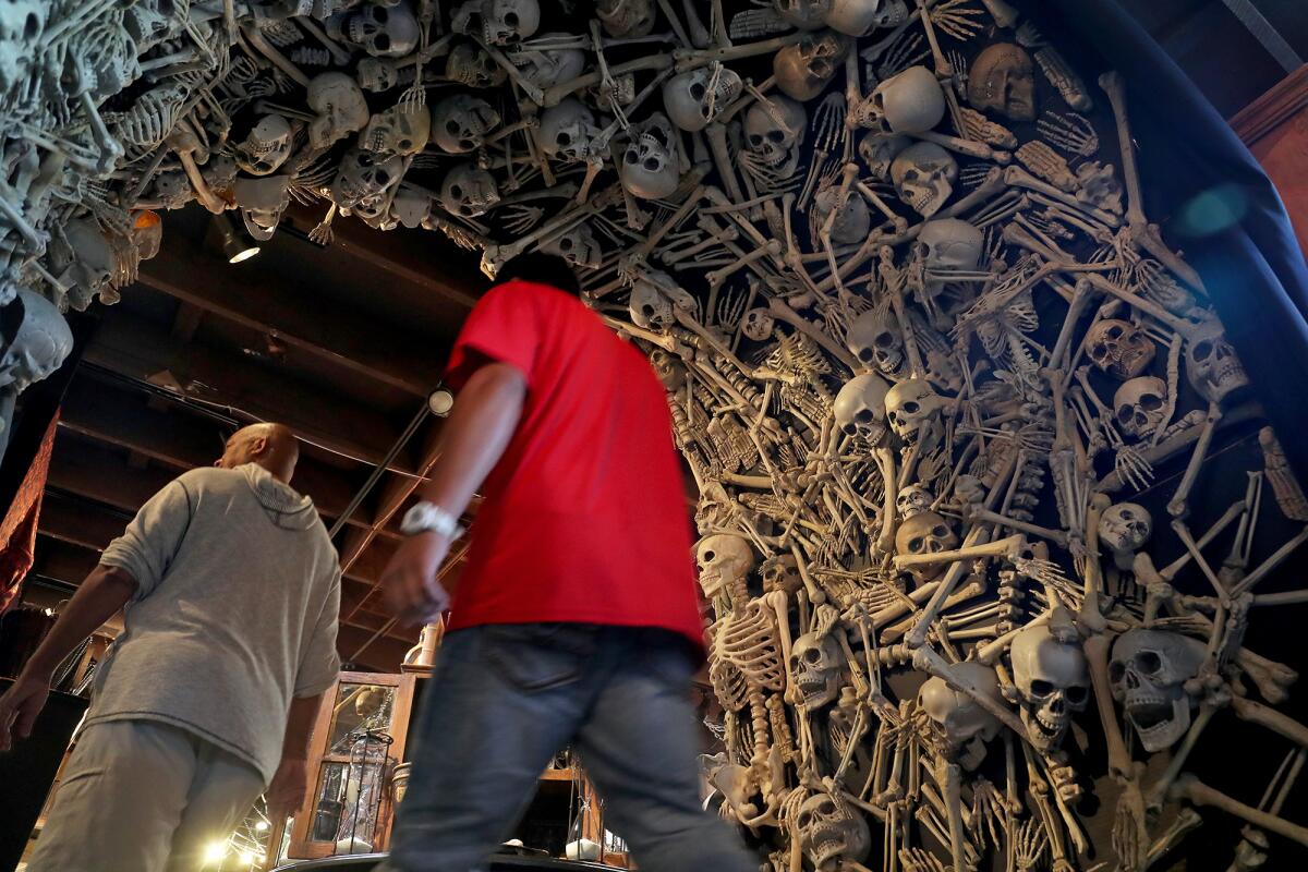 Shoppers walk under an archway lined with faux human skeletons Thursday at Roger's Gardens in Corona del Mar.