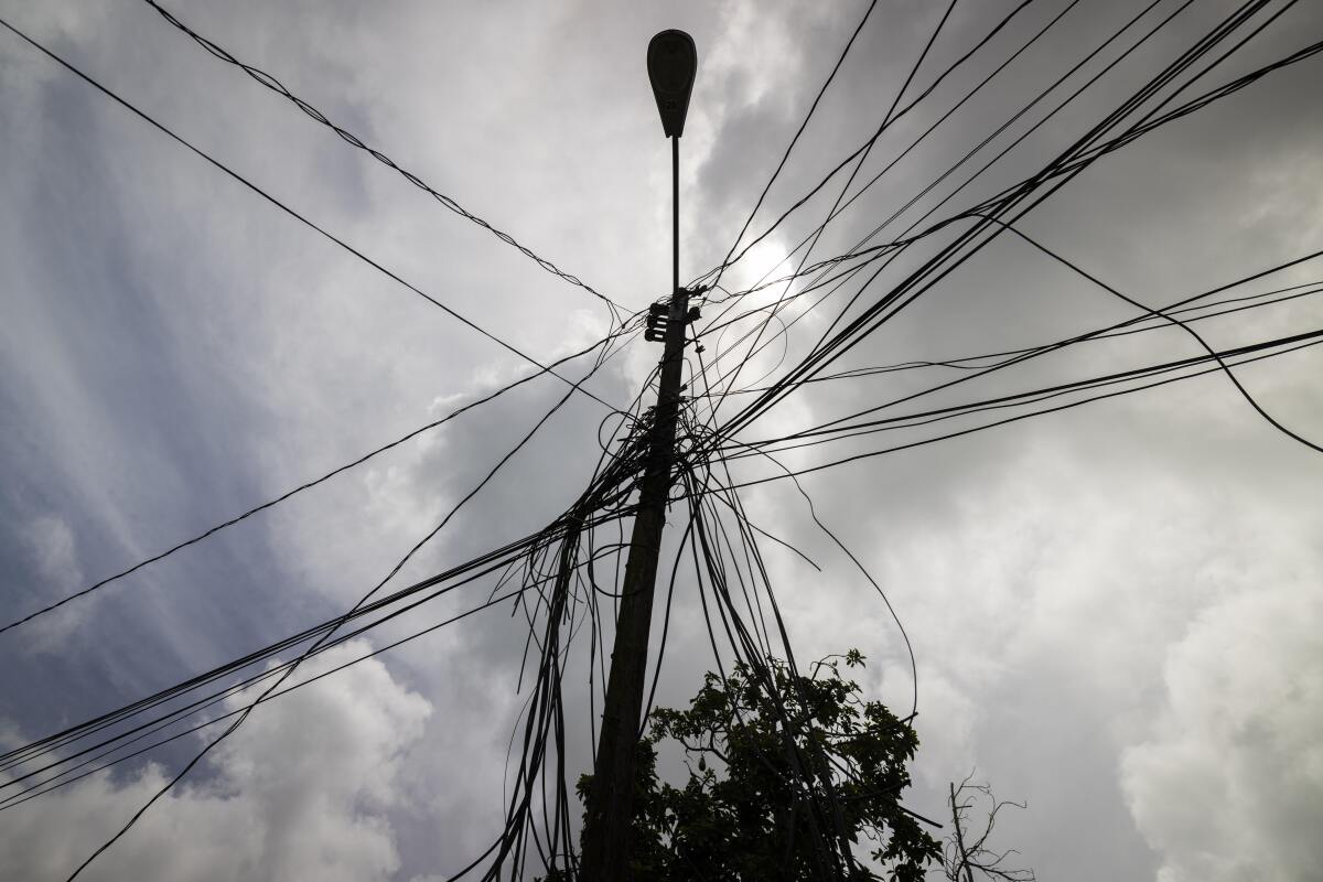 A utility pole with loose cables towers over a home in Loiza, Puerto Rico.
