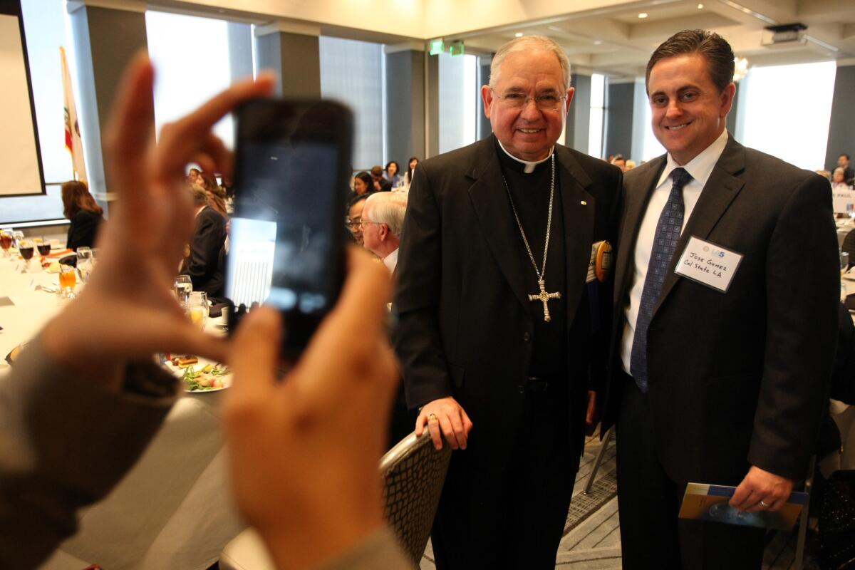 Los Angeles Archbishop Jose Gomez, left, poses for a photo with Jose A. Gomez, vice president and chief of staff at Cal State Los Angeles, before the archbishop delivered a speech on immigration reform at the Rotary Club luncheon at City Club in downtown Los Angeles on Friday.