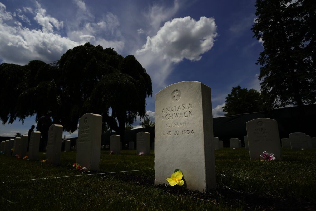 A flower sits at the base of headstone at the cemetery of the U.S. Army's Carlisle Barracks, Friday, June 10, 2022, in Carlisle, Pa. The Army is continuing a multi-phase project to disinter the remains of indigenous children who died more than a century ago while attending a government-run boarding school at the site and reunite them with their families. (AP Photo/Matt Slocum)
