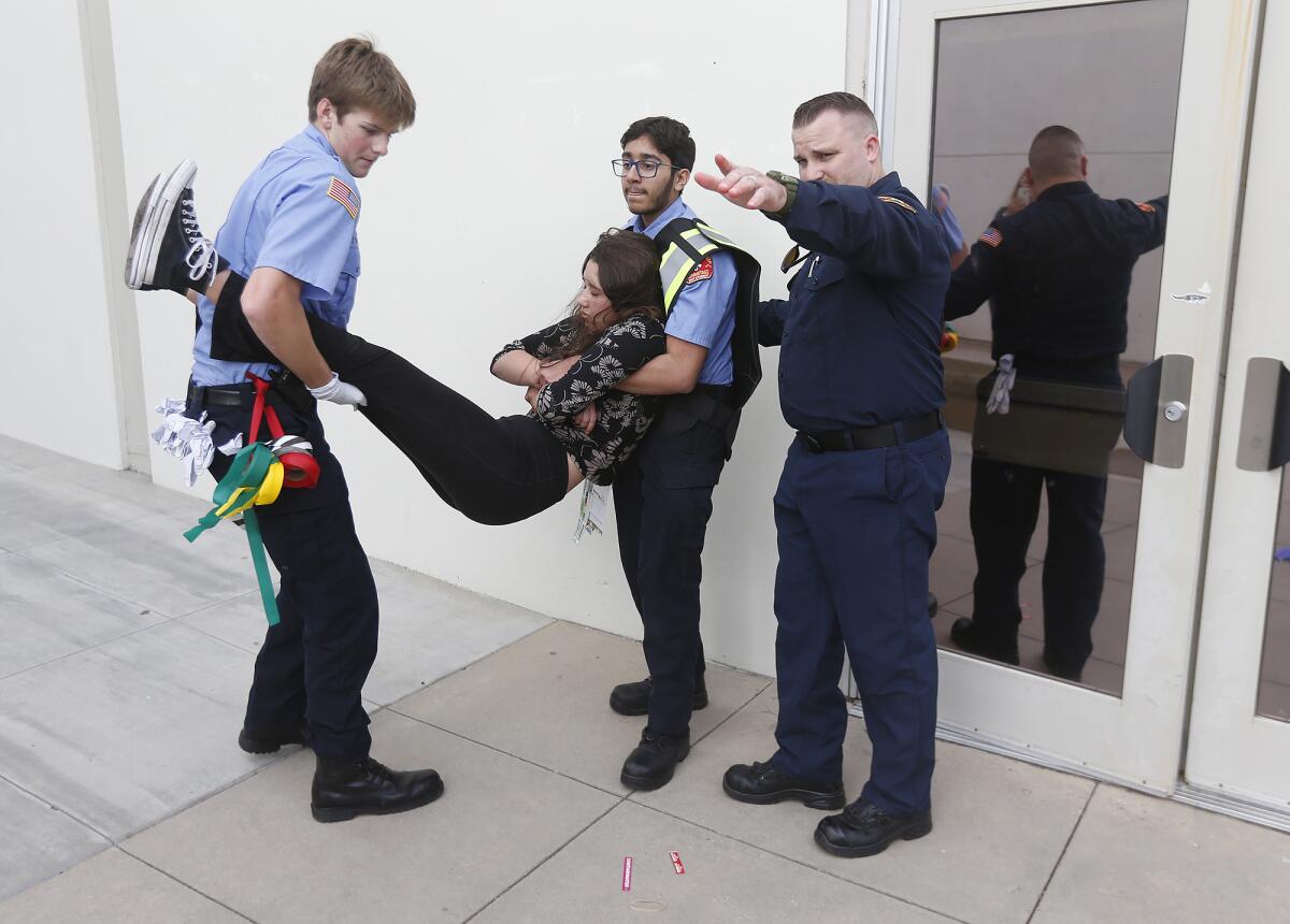 EMT instructor Eric Johnson helps students carry a victim of a simulated zombie apocalypse.