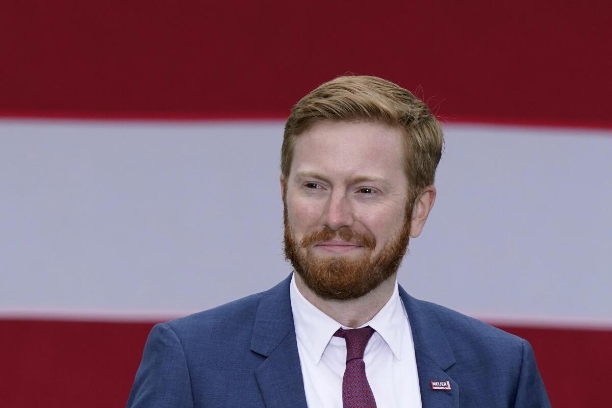 A man with a beard in a blue suit with maroon tie