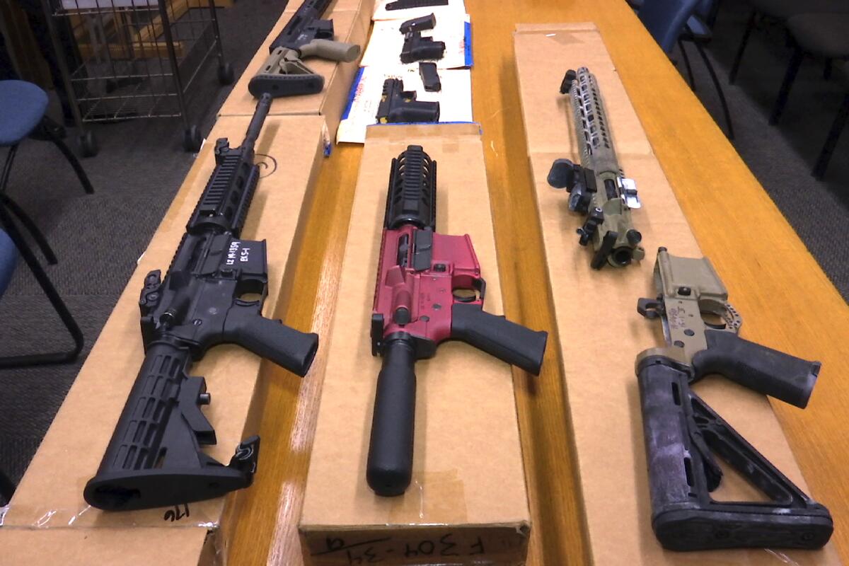 Rifles and handguns assembled from polymer kits are laid out on a table