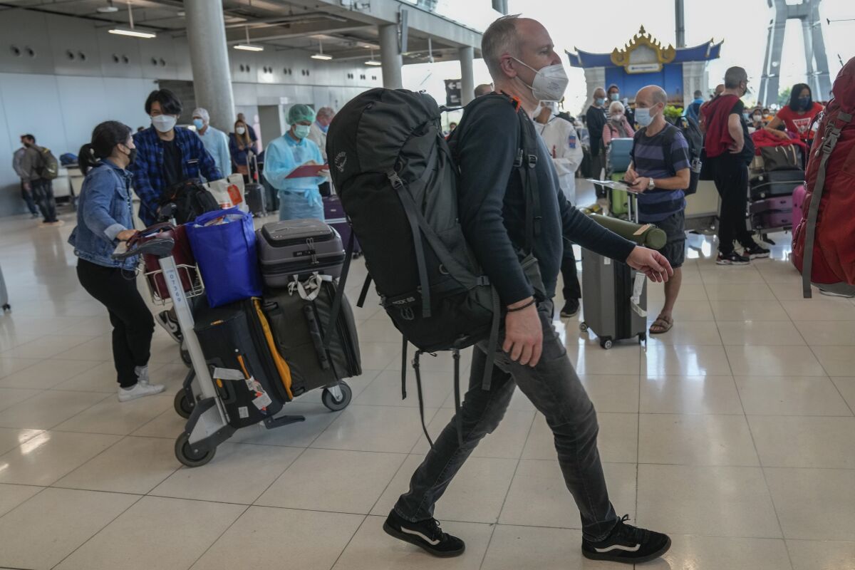 Tourists arrive at Suvarnabhumi International Airport in Bangkok, Thailand, Monday, Nov. 1, 2021. Thailand was reopening its border Monday. Fully vaccinated tourists arriving by air from 46 countries and territories no longer have to quarantine and can move freely. (AP Photo/Sakchai Lalit)