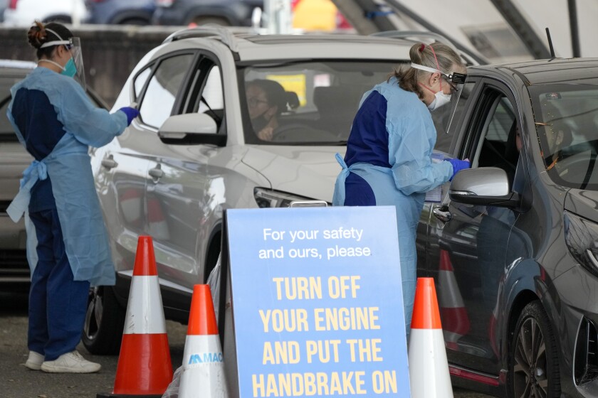 Staff collect samples at a drive-through COVID-19 testing clinic at Bondi Beach in Sydney, Australia, Saturday, Jan. 8, 2022. Australia's most populous state has reinstated some restrictions and suspended elective surgeries as COVID-19 cases surged to another record. (AP Photo/Mark Baker)