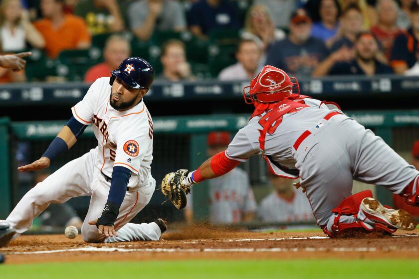 Astros' Marwin Gonzalez (9) slides around Angels catcher Carlos Perez (58), who loses control of the ball in the first inning.