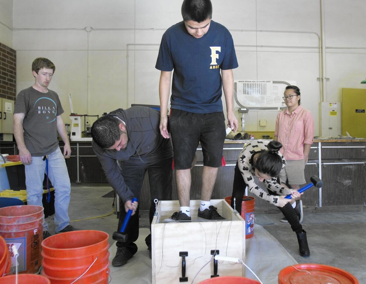 Cal State Fullerton undergraduate students John Stapleton, left, Luis Camacho, Daniel Macias, Rosalie Chavez and Alexandra San Pablo test a project for an upcoming competition in the engineering building.