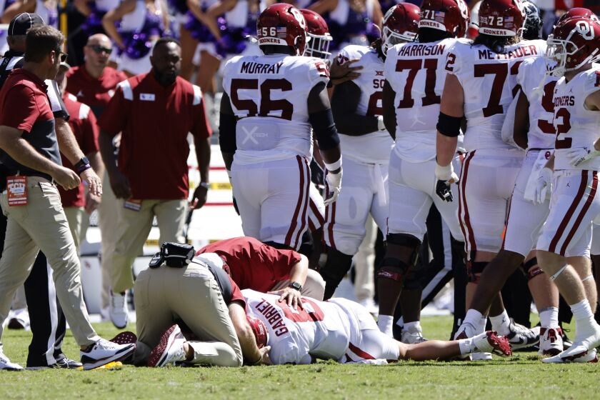 Oklahoma quarterback Dillon Gabriel (8) its looked at by team staff after a late hit by TCU during the first half of an NCAA college football game Saturday, Oct. 1, 2022, in Fort Worth, Texas. (AP Photo/Ron Jenkins)