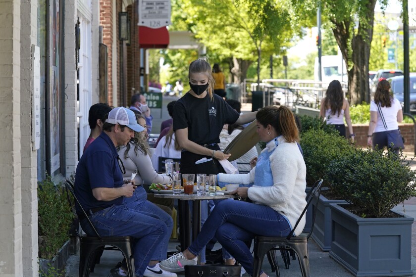 FILE - In this April 16, 2021 file photo, patrons are assisted while dining along a sidewalk in Chapel Hill, N.C. You and your friends likely have different amounts of money to spend on dinners, movies and other social activities. One friend may think nothing of dropping $50 on a concert ticket, while another may need that cash for bills. So how can friends manage these differences as they reenter the expensive world of socializing? (AP Photo/Gerry Broome, File)