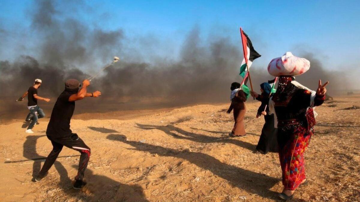 Palestinian protesters throw stones at Israeli forces during a demonstration at the Israel-Gaza border on Friday.