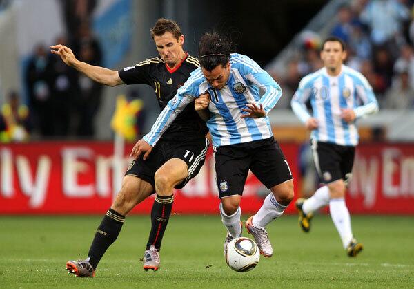 Miroslav Klose of Germany challenges Carlos Tevez of Argentina during the 2010 FIFA World Cup South Africa Quarter Final match between Argentina and Germany at Green Point Stadium on July 3, 2010 in Cape Town, South Africa.