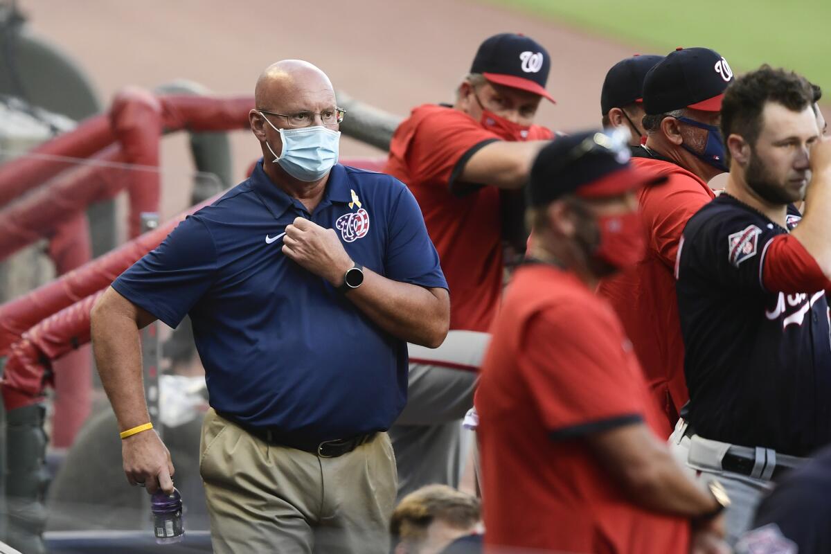 Washington Nationals general manager Mike Rizzo, left, looks on from the dugout during a game against the Atlanta Braves