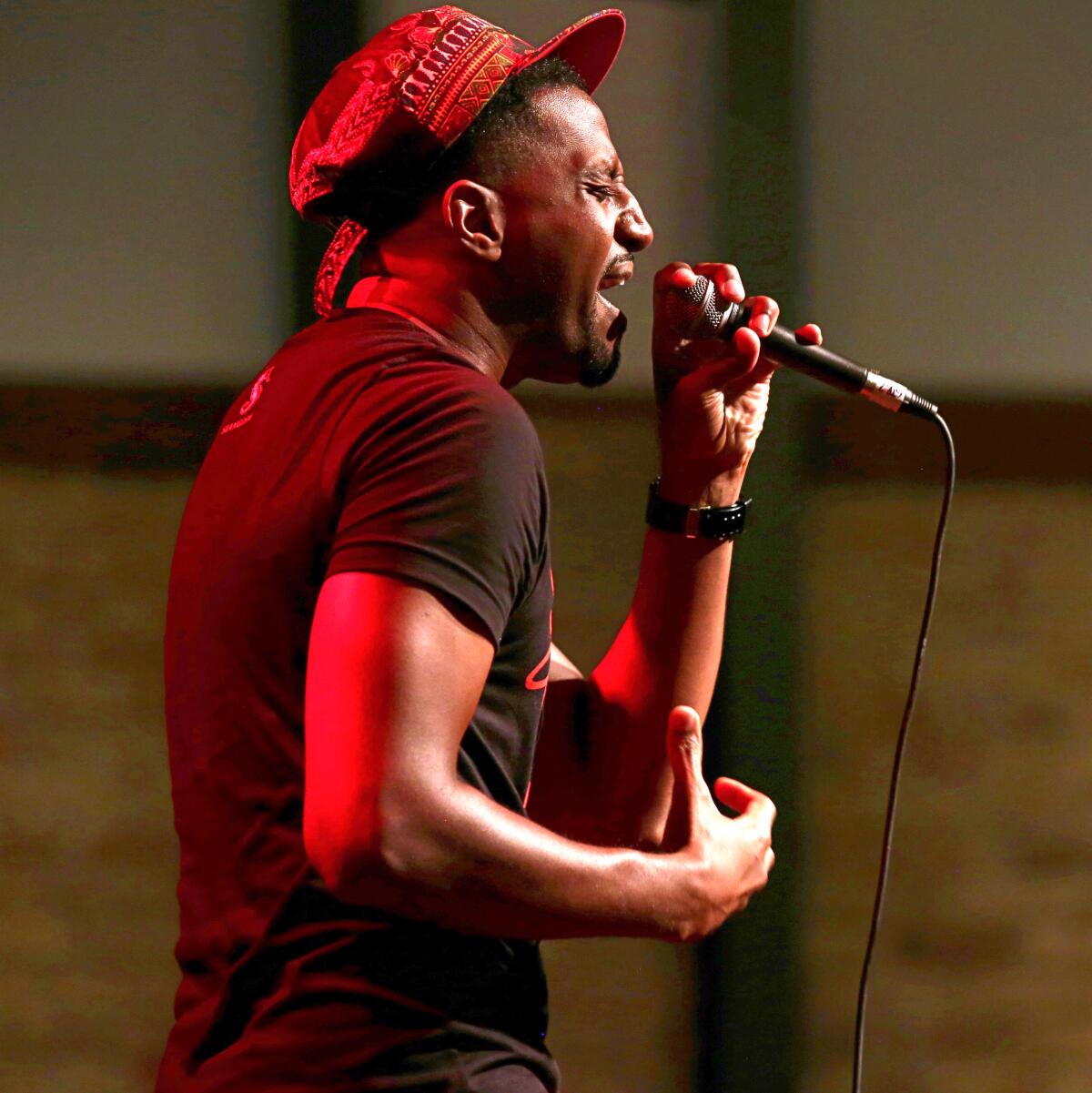 A man in a cap sings passionately into a microphone.