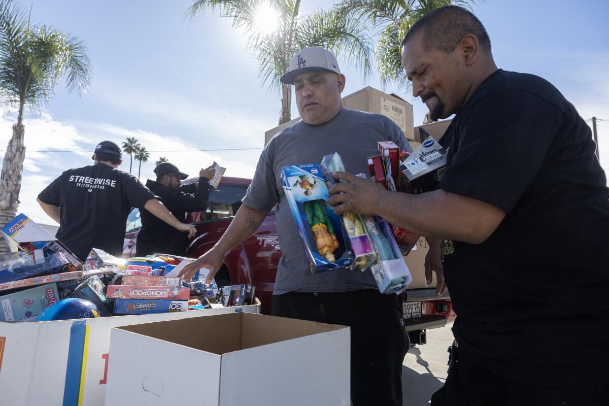 Victory Outreach Church members Chuck Ortega and Mario Munoz gather toys in boxes.
