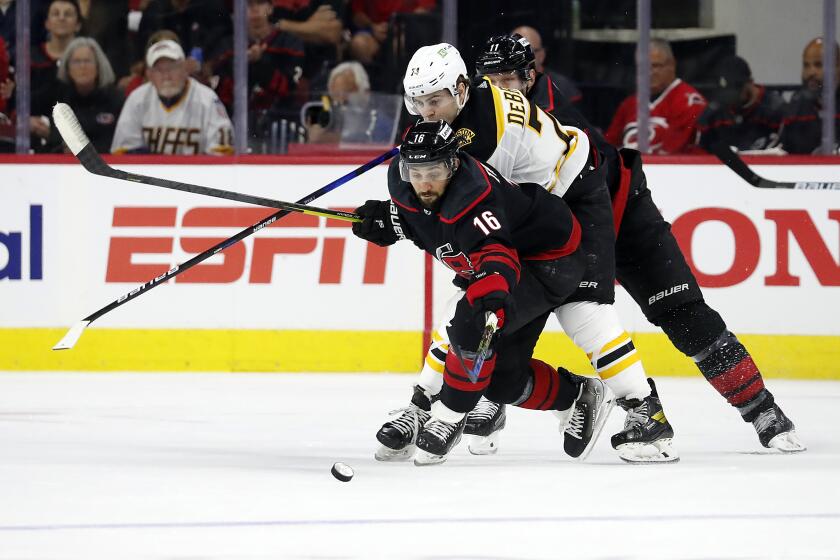 Carolina Hurricanes' Vincent Trocheck (16) reaches for the puck in front of Boston Bruins' Jake DeBrusk (74) during the second period of Game 1 of an NHL hockey Stanley Cup first-round playoff series in Raleigh, N.C., Monday, May 2, 2022. (AP Photo/Karl B DeBlaker)