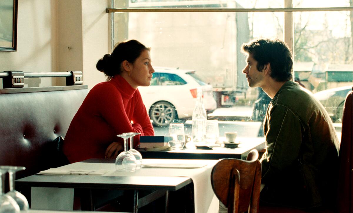 A man and a woman sit in a restaurant in front of a window