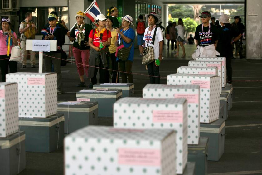 Anti-government protesters stand by empty ballot boxes as they block a district office in an attempt to stop the elections Sunday in Bangkok, Thailand.