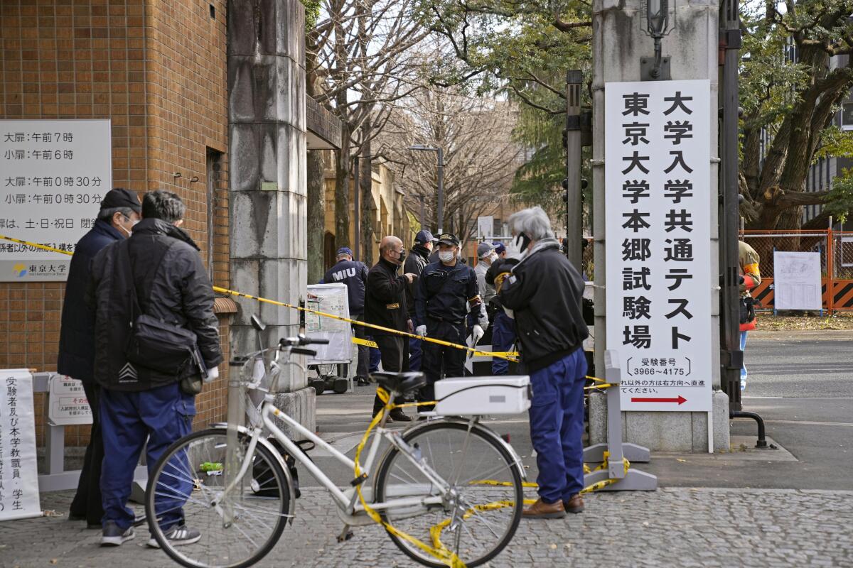 Police officers inspect the site of a stabbing near the compound of Tokyo University in Tokyo, Japan, Saturday, Jan. 15, 2022. Three people, including two students on their way to take university entrance exams, were stabbed Saturday just outside of a test venue, and the authorities arrested a 17-year-old student at the scene on suspicion of attempted murder, Tokyo police said. (Ren Onuma/Kyodo News via AP)