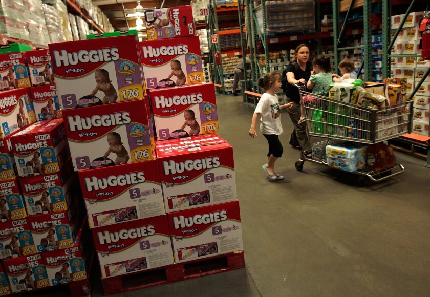 A family passes by bulk packages of diapers at a Costco store in Tucson, Ariz.