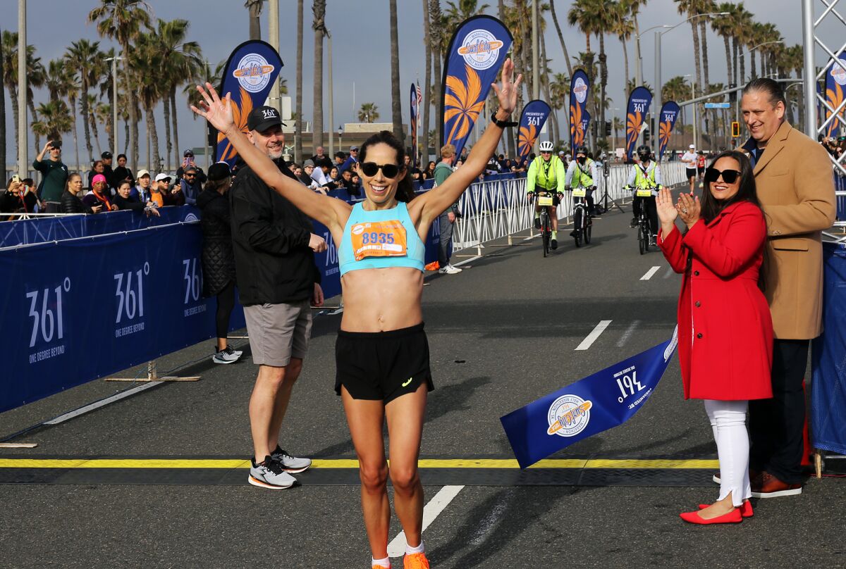 Elizabeth Camy of Simi Valley is all smiles after winning the women's Surf City Half Marathon on Sunday.