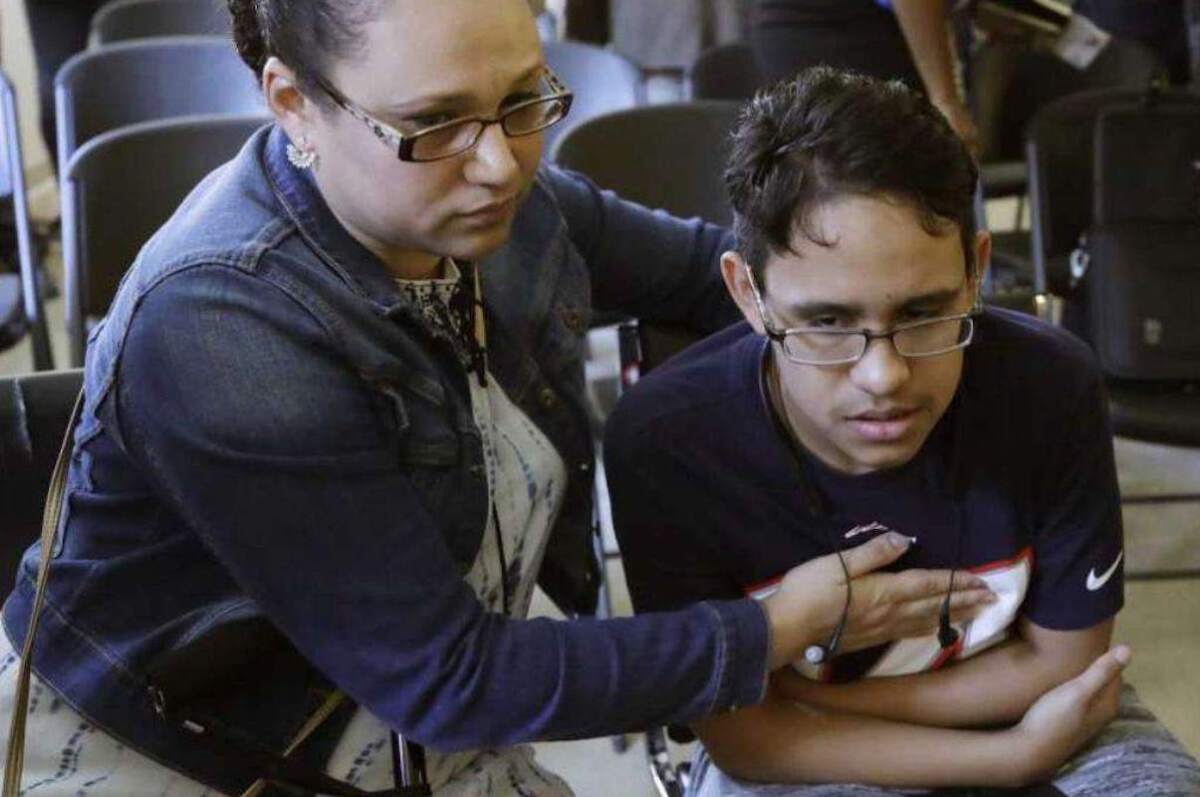 La hondureña Mariela Sánchez consuela a su hijo Jonathan, de 16 años, durante una conferencia de prensa en Boston. La familia Sánchez viajó a Estados Unidos en busca de tratamiento médico para Jonathan, quien sufre de fibrosis quística.