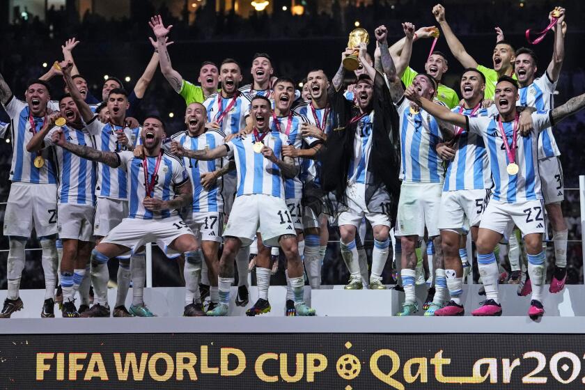 Argentina's Lionel Messi holds up the trophy in front of his teammates after winning the World Cup