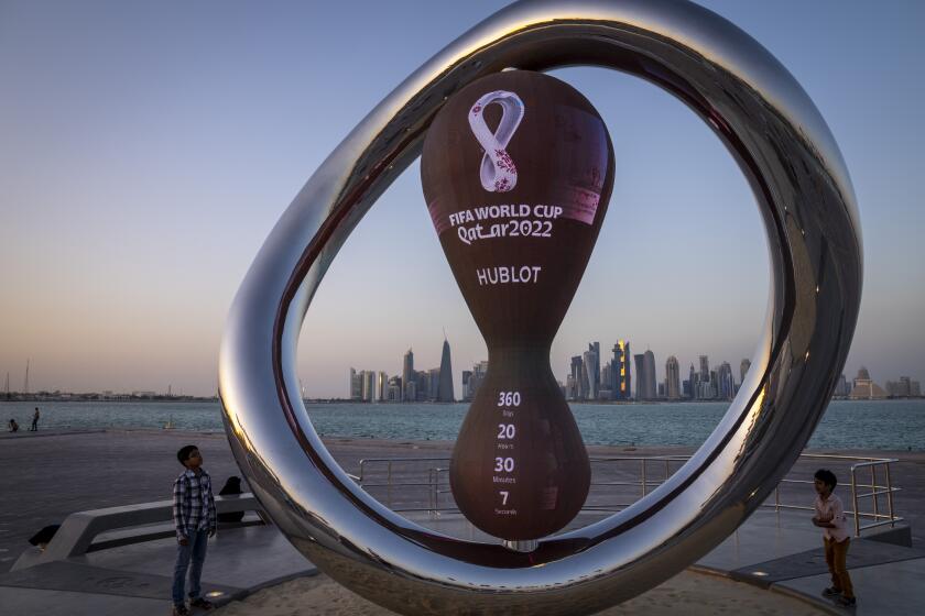 FILE - Children stand next to the official countdown clock showing remaining time until the kick-off of the World Cup 2022, in Doha, Qatar, Nov. 25, 2021. Fans can start registering for the lottery to buy Qatar World Cup tickets Wednesday, Jan. 19, 2022. FIFA tickets will be distributed through a ballot process rather than an open sale for the Nov. 21-Dec. 18 tournament. (AP Photo/Darko Bandic, file)