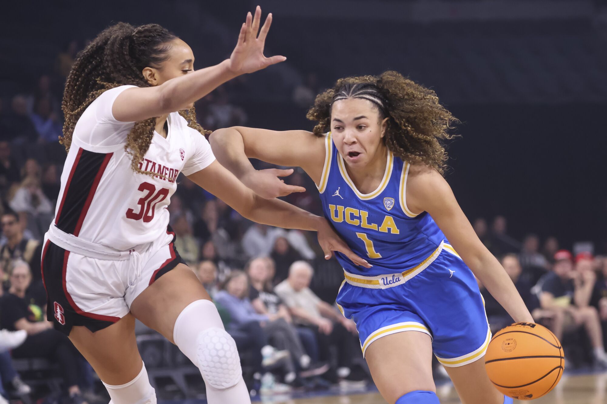 UCLA guard Kiki Rice, right, drives to the basket under pressure from Stanford guard Haley Jones.