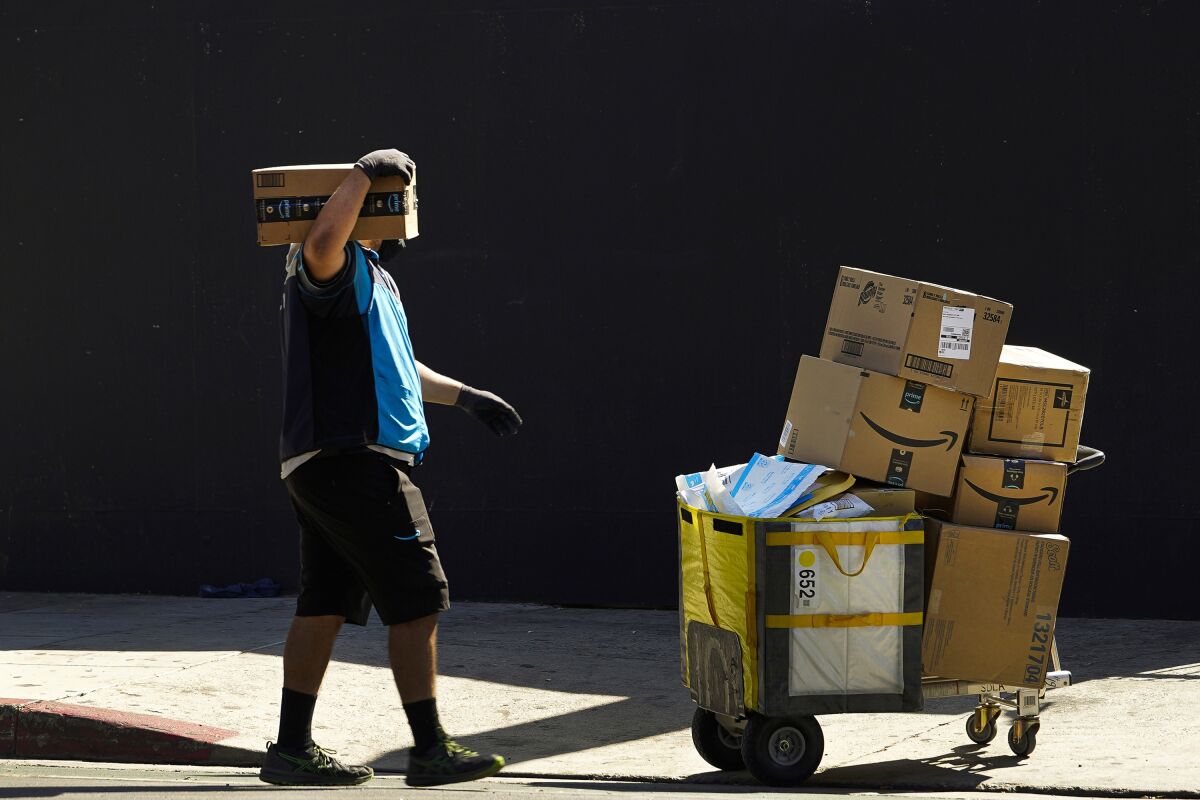 FILE - An Amazon worker delivers boxes in Los Angeles on Oct. 1, 2020. Amazon said Wednesday, Sept. 28, 2022, that it is raising its average starting pay for frontline workers from $18 to $19 a hour, a boost that could help it attract more employees in a tight labor market as the holiday season approaches. (AP Photo/Damian Dovarganes, File)