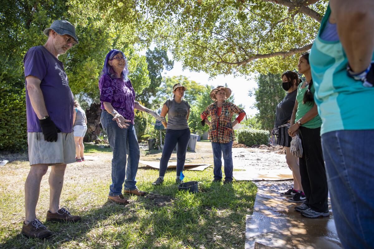 Leigh Adams, center, talks with volunteers during a sheet mulching workshop at the Maryknoll Sisters retirement home.