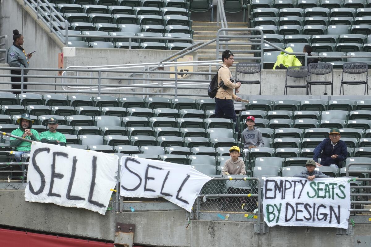 Fans at a game between the Athletics and Houston Astros in Oakland on May 28, 2023, hang signs protesting owner John Fisher.