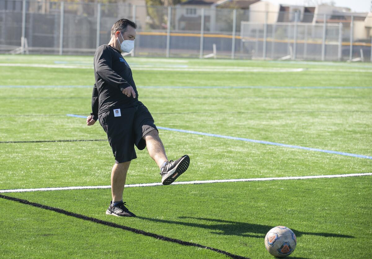 Bryan Middleton, the girls' soccer coach, kicks a ball around on the new soccer field at Corona del Mar High School.