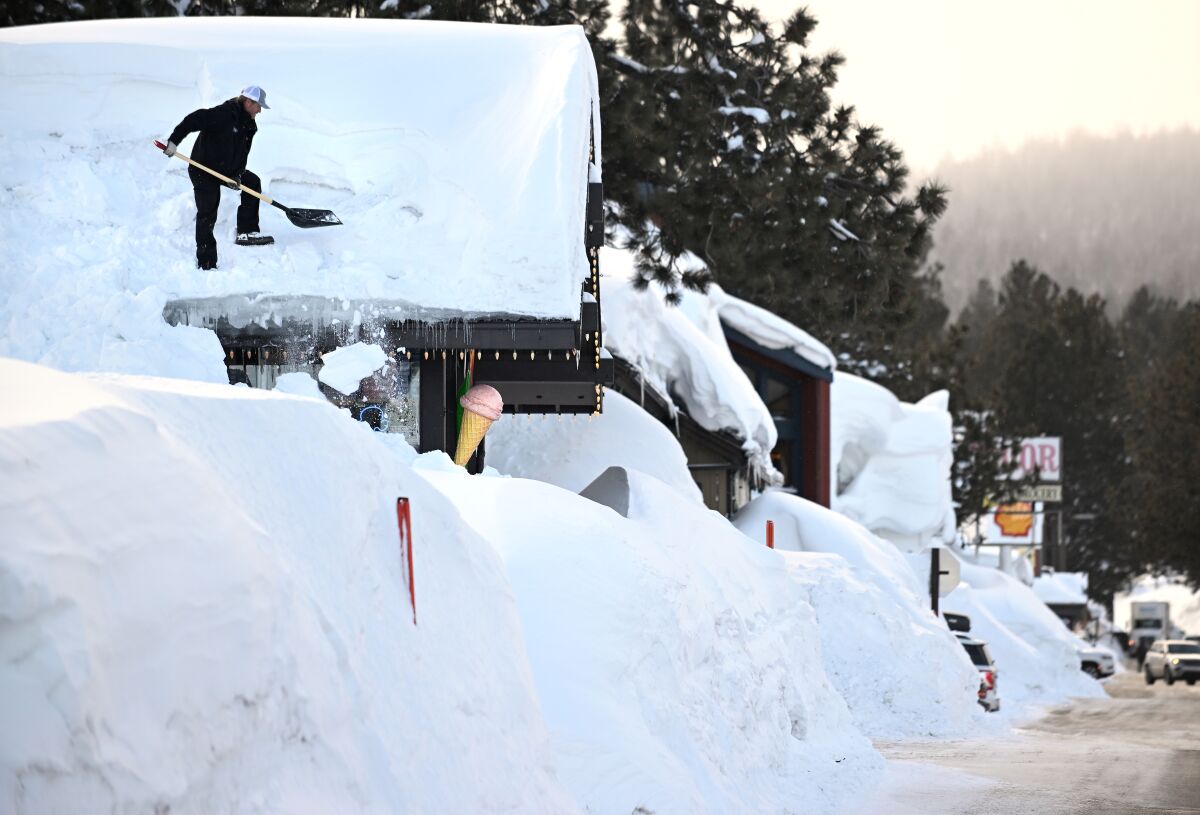 Brang Miller, owner of Mammoth Fun Shop, shovels snow off the roof of his store in Mammoth Lakes.