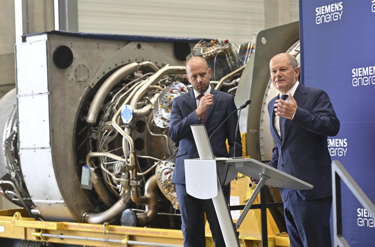 German Chancellor Olaf Scholz, right, stands besides Christian Bruch, CEO of Siemens Energy, at the turbine serviced in Canada for the Nordstream 1 natural gas pipeline in Muelheim an der Ruhr, Germany, Aug. 3, 2022. German Chancellor Olaf Scholz visited a plant by Siemens Energy where a turbine, which is at the center of a dispute between Germany and Russia over reduced gas supplies, is currently sitting in storage until it can be shipped to Russia. (Bernd Thissen/dpa via AP)