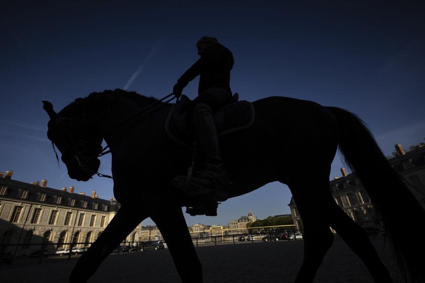 A horsewoman trains with her horse in the main courtyard of the royal stables, in Versailles, Thursday, April 25, 2024. More than 340 years after the royal stables were built under the reign of France's Sun King, riders and horses continue to train and perform in front of the Versailles Palace. The site will soon keep on with the tradition by hosting the equestrian sports during the Paris Olympics. Commissioned by King Louis XIV, the stables have been built from 1679 to 1682 opposite to the palace's main entrance. (AP Photo/Aurelien Morissard)