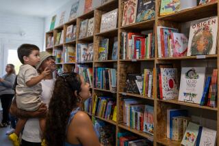 Zaden Alvarez, 2, and his parents Eric Alvarez and Sandy Andrade look for a book to read from LA libreria's bookcase 