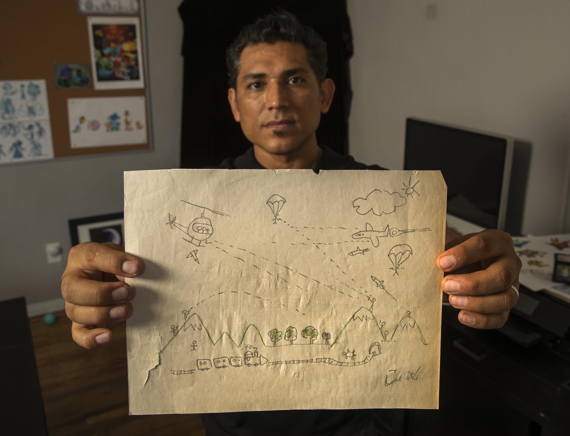 Disney character designer Jose Zelaya holds a drawing he did as a boy, depicting the war in El Salvador, where he grew up.