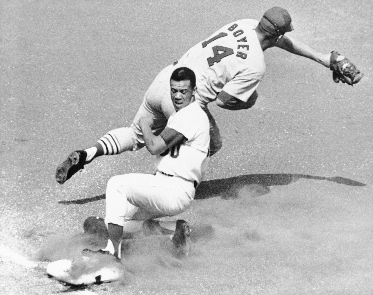 The Dodgers' Maury Wills slips safely into third place while the 1965 St. Louis Cardinals' Ken Boyer makes the toss.