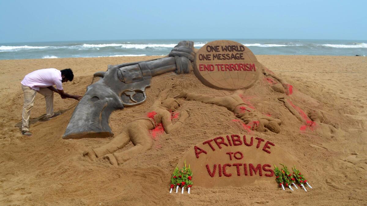Indian sand artist Sudarsan Pattnaik puts the finishing touches on a sand sculpture at Puri Beach, India, on Monday, following the attack on a gay nightclub in Orlando, Fla.