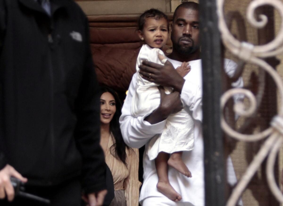 Kanye West holds daughter North as Kim Kardashian looks on inside Armenian St. James Cathedral in Jerusalem on Monday.